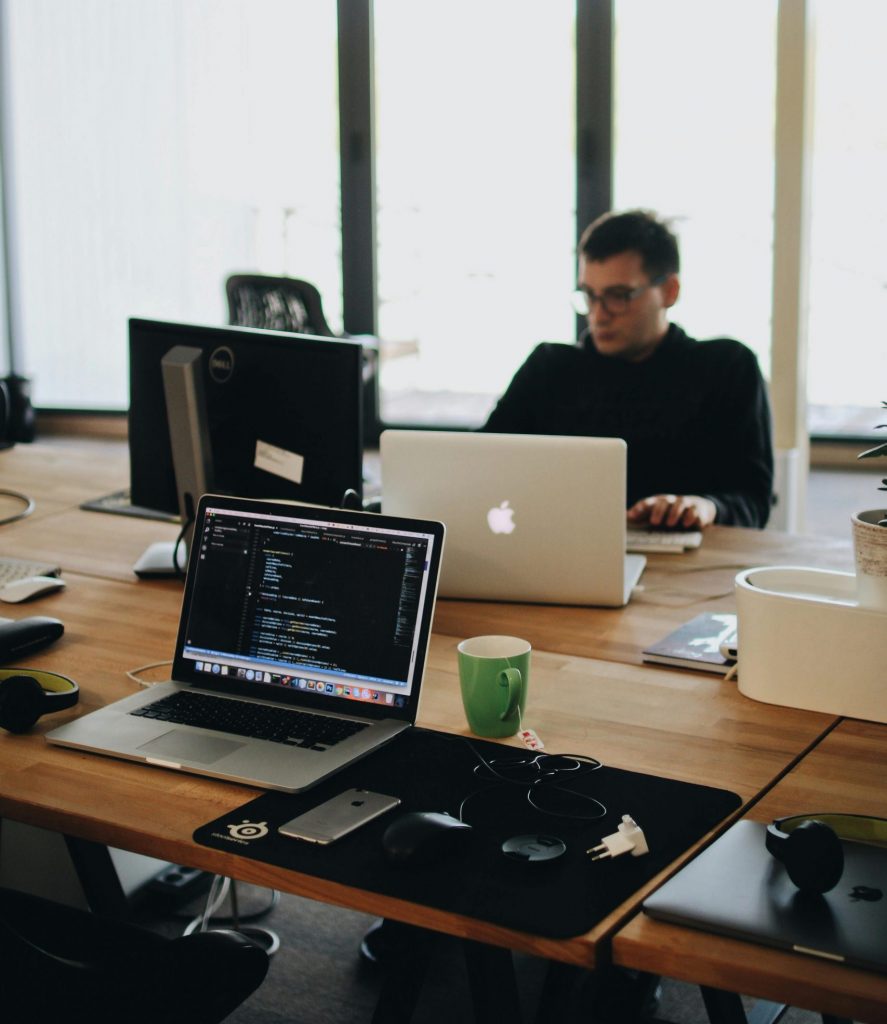 A web developer working on code in a modern office setting with multiple devices.