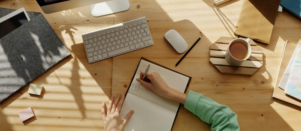 A student taking notes during a video call for online learning at home.