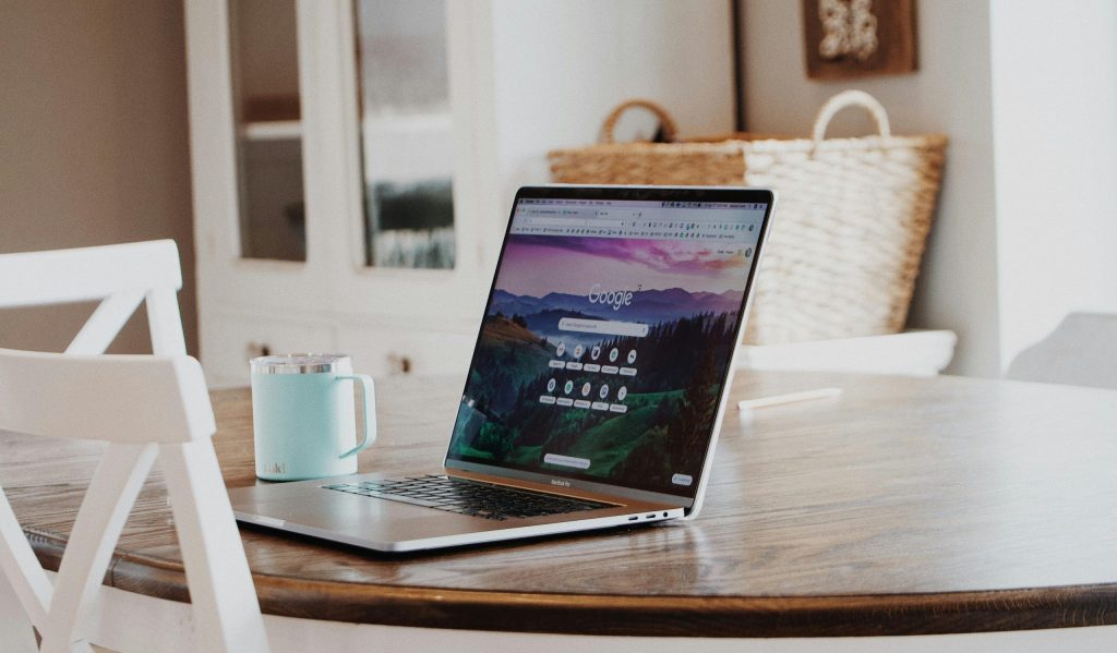 A sleek laptop on a wooden table with a mug, exemplifying a modern home workspace.